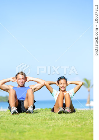 People exercising - Couple doing sit ups outdoors 10037813