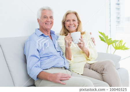 Senior couple with coffee cup sitting on sofa 10040325