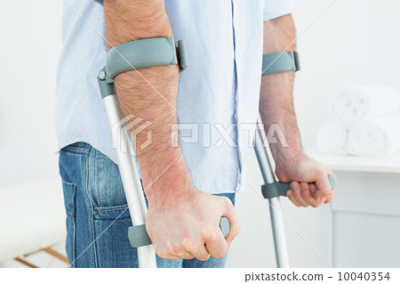 Close-up mid section of a young man with crutches 10040354