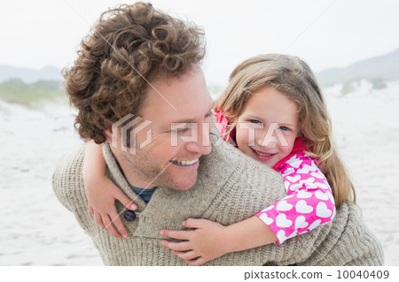 Man piggybacking his daughter at beach Man piggybacking his daughter at beach 10040409