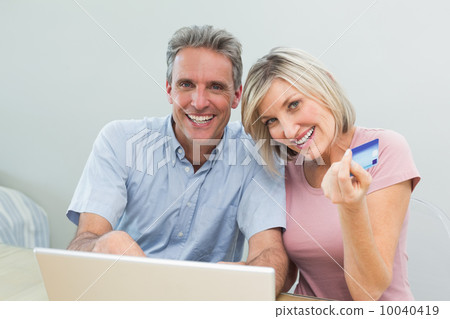Cheerful couple doing online shopping at home 10040419