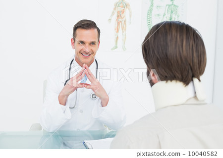 Friendly doctor listening to patient with concentration at desk 10040582