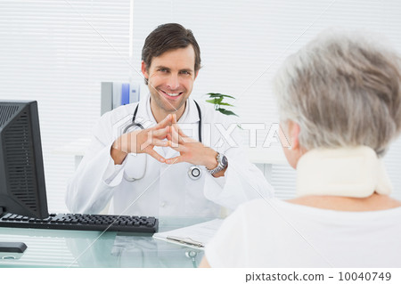 Smiling doctor listening to senior patient at medical office Smiling doctor listening to senior patient at medical office 10040749