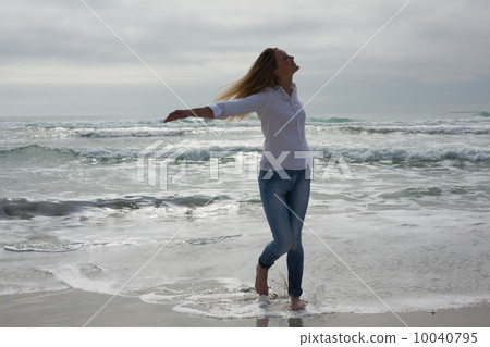 Woman with eyes closed and arms outstretched at beach Woman with eyes closed and arms outstretched at beach 10040795