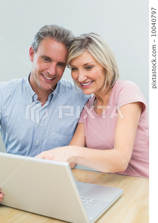Casual couple using laptop at home Casual couple using laptop at home 10040797