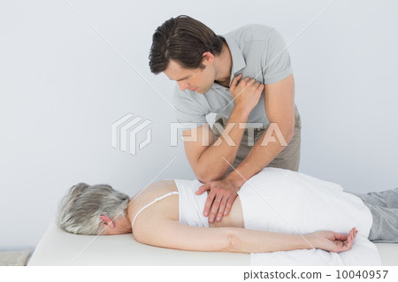 Male physiotherapist massaging a senior woman's back 10040957