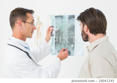 Male doctor explaining spine x-ray to patient 10041245