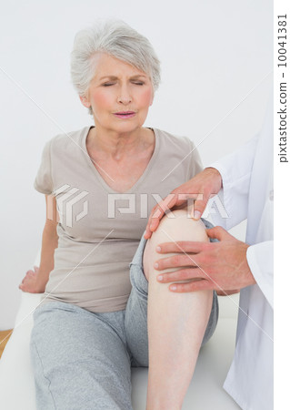 Displeased senior woman getting her knee examined Displeased senior woman getting her knee examined 10041381