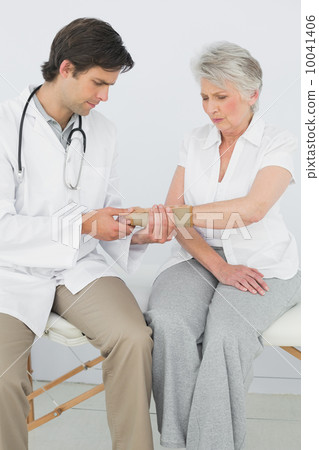 Male physiotherapist examining a senior woman's wrist 10041406