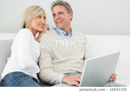 Happy casual couple using laptop in at home 10041505