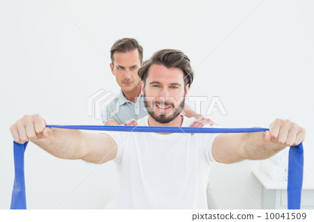 Male therapist assisting young man with exercises 10041509