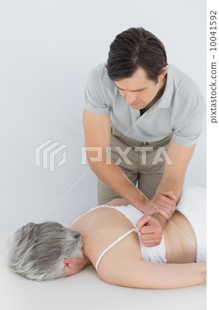 Male physiotherapist massaging a senior woman's back 10041592