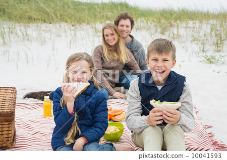 Happy family of four at a beach picnic Happy family of four at a beach picnic 10041593