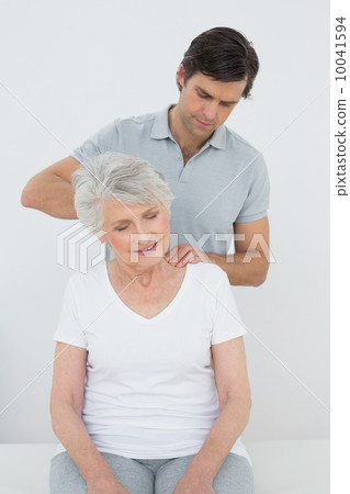 Male physiotherapist massaging a senior woman's neck 10041594