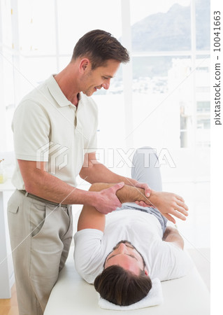 Male physiotherapist examining a young man's hand Male physiotherapist examining a young man's hand 10041663