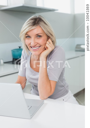 Casual happy woman with laptop in kitchen 10041869