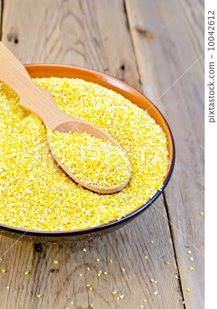 Corn grits in bowl with spoon on board 10042612