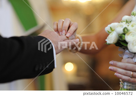 Bride putting a ring on groom's finger Bride putting a ring on groom's finger 10046572