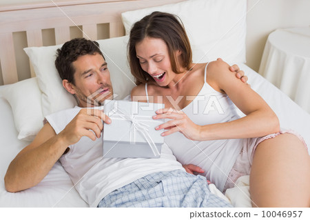 Couple with gift box lying together in bed 10046957