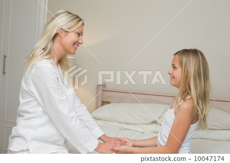 Mother and daughter holding hands in bed Mother and daughter holding hands in bed 10047174