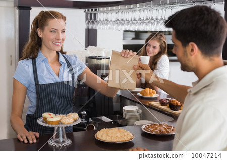 Cafe owner giving packed food to a couple at coffee shop Cafe owner giving packed food to a couple at coffee shop 10047214