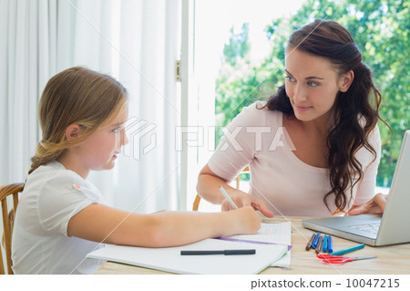 Woman with laptop assisting daughter in homework Woman with laptop assisting daughter in homework 10047215