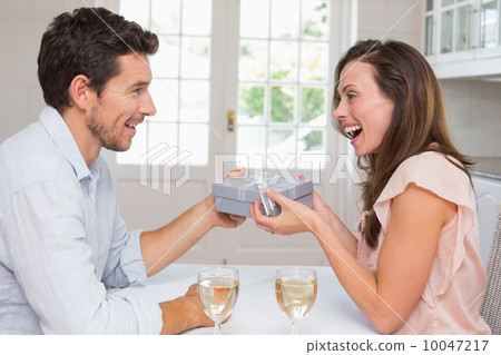 Man giving happy woman a gift box at home Man giving happy woman a gift box at home 10047217