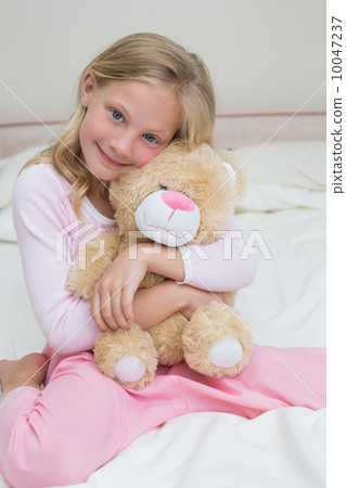 Young girl embracing stuffed toy in bed 10047237