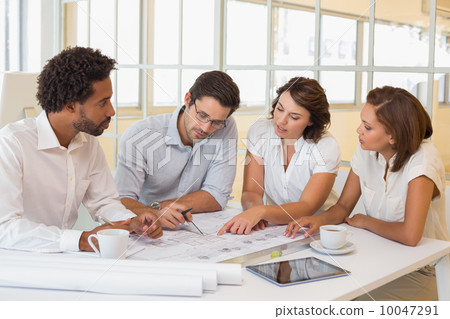 Colleagues working on blueprints in office Colleagues working on blueprints in office 10047291