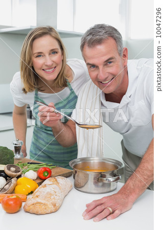 Couple preparing food together in kitchen Couple preparing food together in kitchen 10047296