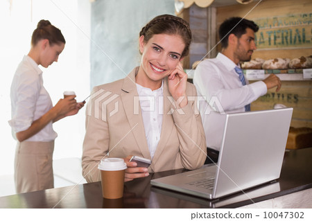 Businesswoman using laptop in office cafeteria Businesswoman using laptop in office cafeteria 10047302