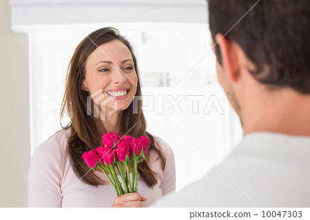Cheerful woman looking at man with flowers Cheerful woman looking at man with flowers 10047303
