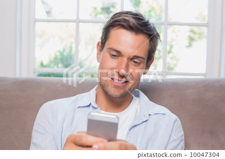 Casual man reading text message on sofa Casual man reading text message on sofa 10047304