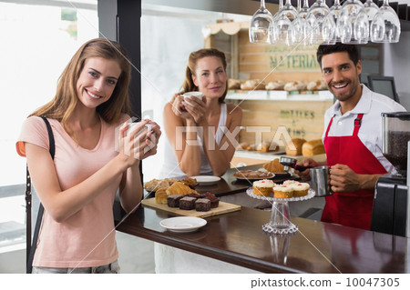 Woman drinking coffee with friend and male barista in coffee sho Woman drinking coffee with friend and male barista in coffee sho 10047305