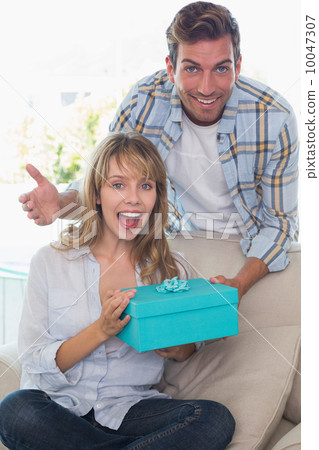 Man surprising woman with a gift in the living room Man surprising woman with a gift in the living room 10047307