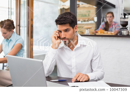 Man using mobile phone in coffee shop Man using mobile phone in coffee shop 10047309