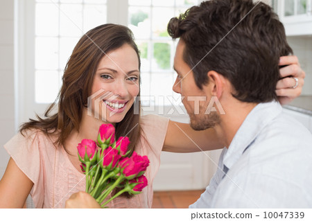 Happy woman and man with flowers at home Happy woman and man with flowers at home 10047339