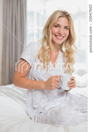Beautiful casual woman holding coffee cup in bed Beautiful casual woman holding coffee cup in bed 10047605