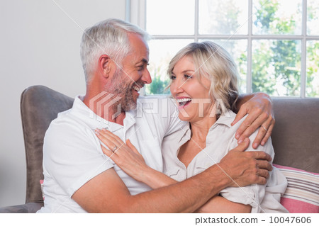 Cheerful mature couple sitting on couch Cheerful mature couple sitting on couch 10047606