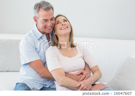 Happy couple embracing in the living room 10047607