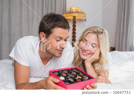 Young couple with candies resting in bed 10047751