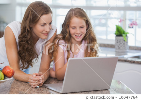 Girl and mother using laptop in house 10047764