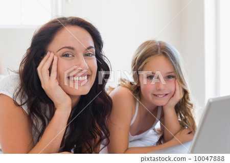 Mother and daughter with laptop lying in bed Mother and daughter with laptop lying in bed 10047888