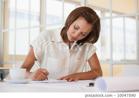 Businesswoman working on blueprint in office Businesswoman working on blueprint in office 10047890
