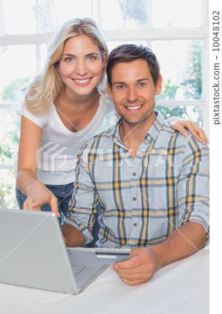 Smiling young couple doing online shopping at home Smiling young couple doing online shopping at home 10048102