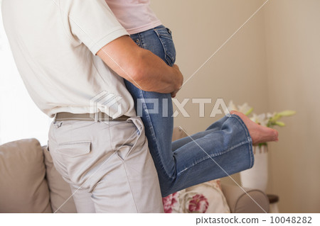 Man carrying woman in living room Man carrying woman in living room 10048282