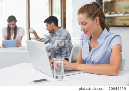 Woman using laptop in coffee shop Woman using laptop in coffee shop 10048319