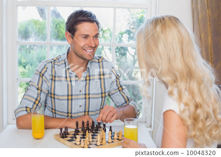 Couple playing chess while having orange juice at home Couple playing chess while having orange juice at home 10048320