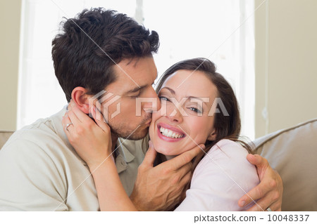 Loving young man kissing woman in living room 10048337