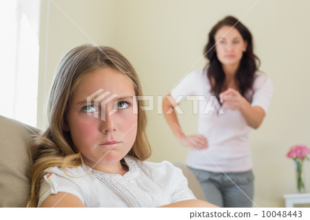Angry girl with mother scolding her in background Angry girl with mother scolding her in background 10048443